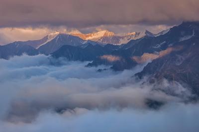Schneebedeckte Berggipfel ragen aus einem Wolkenmeer.